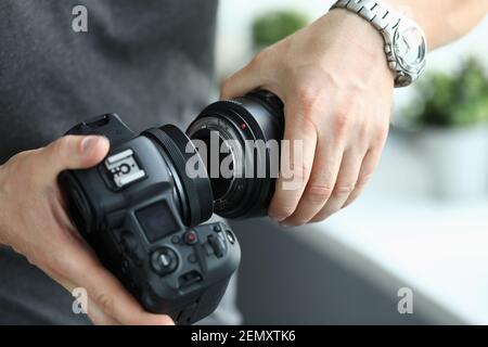 Mani maschili che indossano l'obiettivo professionale della fotocamera digitale moderna Foto Stock