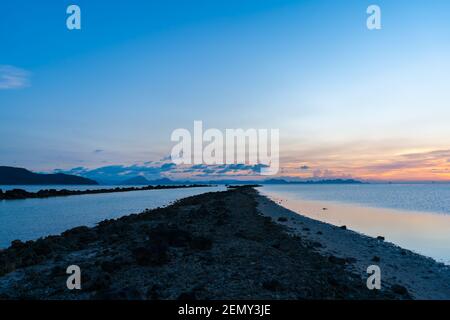 Meraviglioso paesaggio del tramonto sulla riva, colori del cielo del tramonto e silhouette dell'isola in acqua. Incredibile tramonto tropicale. Foto Stock