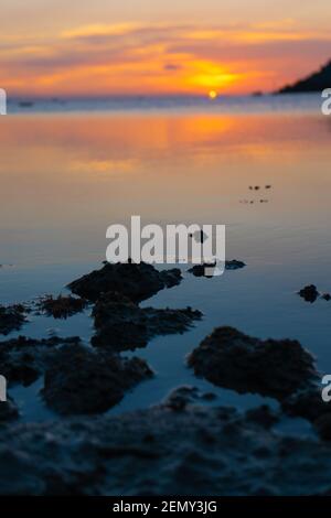 Meraviglioso paesaggio del tramonto sulla riva, colori del cielo del tramonto e silhouette dell'isola in acqua. Incredibile tramonto tropicale. Foto Stock