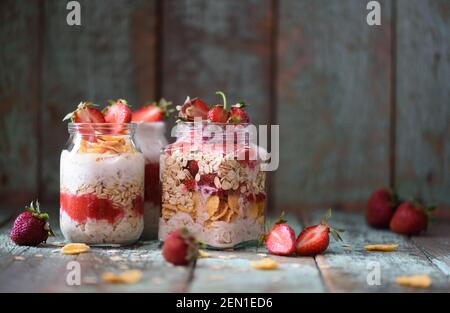 Gustosa e sana colazione. Durante la notte, farinata d'avena cruda in vasetti con fragole biologiche su sfondo turchese copyspace Foto Stock