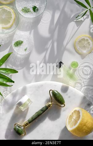 Fondo cosmetico per la cura della pelle. Medicina erboristica con foglie di palma e fette di limone. Luce solare naturale, ombre. Schizzi d'acqua. Vetreria chimica Foto Stock