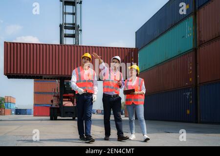 Caposquadra asiatico che cammina e spiega le varie operazioni nel terminal del deposito container al lavoratore. Foto Stock