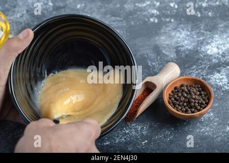 Uomo che mescola l'uovo in una ciotola nera. Foto Stock