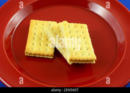 Sandwich Cracker con pomodoro al basilico ripieno su piatto rosso Foto Stock