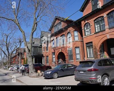 Toronto, Canada - 22 aprile 2018: Centro città strada gentrifed con vecchie case vittoriane e parcheggio consentito sul marciapiede anteriore. Foto Stock