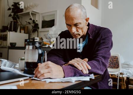 Triste uomo anziano a tavola in soggiorno Foto Stock
