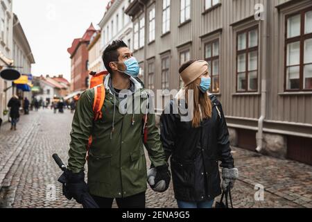 Coppia eterosessuale che tiene le mani mentre esplorando la città durante COVID-19 Foto Stock