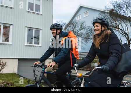Coppia sorridente in bicicletta mentre si esplora la città Foto Stock