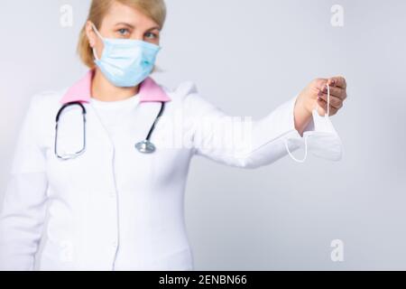 Donna anziana operatrice sanitaria, medico o infermiere che indossa una maschera protettiva monouso che tiene una maschera medica viso, nuovo tipo, infezione da virus di protezione Foto Stock