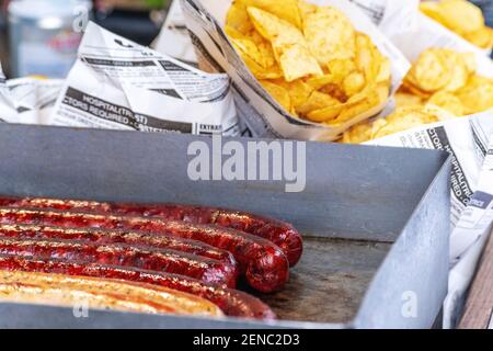 Salsiccia fritta e zeppe di patate fritte in un sacchetto di carta. Concetto di Street food. Foto Stock