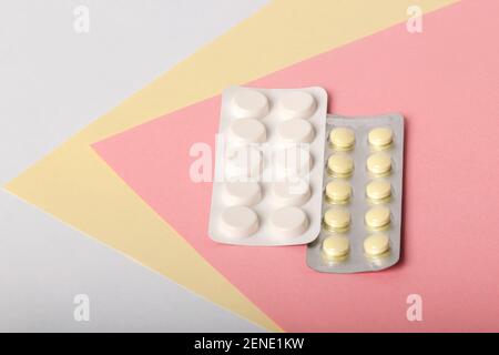 I medicinali bianchi e gialli giacciono su uno sfondo multicolore Foto Stock