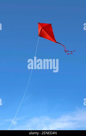 Un aquilone rosso che vola contro un cielo blu intenso Foto Stock