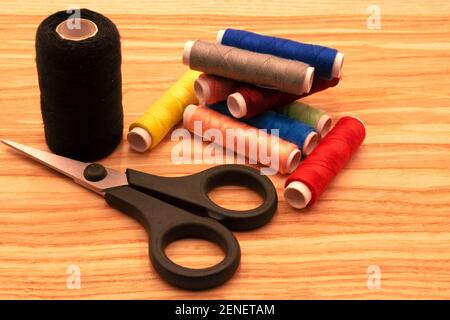 Fotografia dei fili di cucitura multicolore e degli utensili di cucitura sulla luce sfondo di legno Foto Stock