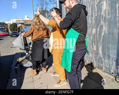 Le celebrazioni per la festa ebraica di Purim (Festival dei lotti) iniziano a Golders Green, North West London, con famiglie e bambini che si godono il cielo blu e il sole mentre si riuniscono in abiti eleganti. Le strade principali sono piene di auto che honking corna nel saluto con molti pedoni che si fermano a chiacchierare e ondare a parenti e amici e scattare fotografie. Londra, Regno Unito. 26 febbraio 2021. Foto Stock
