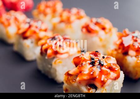 Cibo tradizionale giapponese, Mix sushi colorati Set di diversi tipi di sushi panini con salmone, gamberi e verdure. Su sfondo nero rustico. In alto Foto Stock