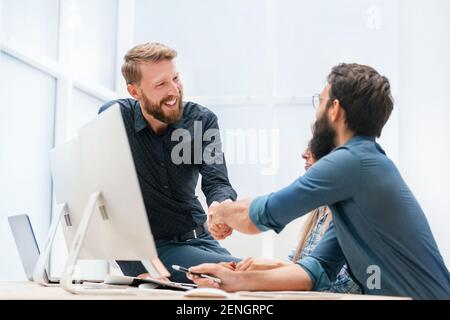 I giovani lavoratori stringono le mani sul posto di lavoro Foto Stock