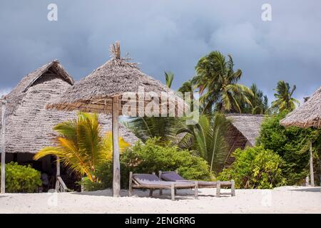 Resort turistico su una spiaggia tropicale con sabbia bianca sotto palme. Lettini e ombrellone. Vacanze da sogno per il clima tropicale. Foto Stock