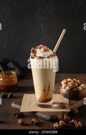 Banana e caramello milkshake guarnito panna montata e popcorn al buio. Foto Stock