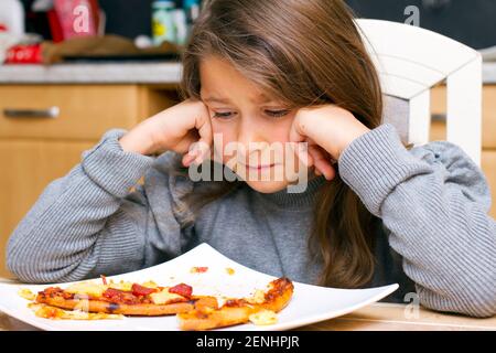 Kind vor Teller mit Pizzaresten, MR: Sì Foto Stock