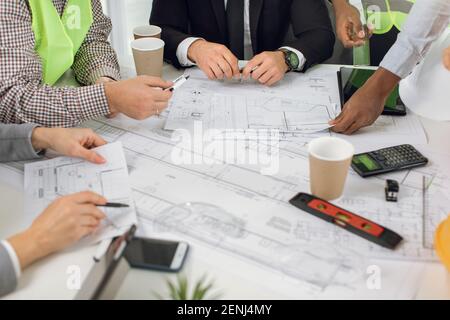 Architetti, ingegneri e progettisti analizzano i progetti, seduti al tavolo Foto Stock