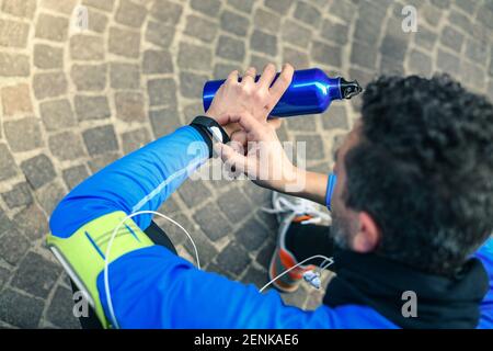 Primo piano delle mani maschili utilizzando l'app fitness su un orologio intelligente. Uomo che riposa dopo aver fatto jogging leggendo i risultati della corsa. Running man con smartwatch che registra i dati in abo Foto Stock