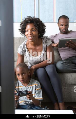Ragazzo la riproduzione di video gioco, madre guardando Foto Stock
