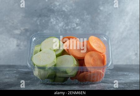 Zucchine e carote affettato in contenitore di plastica su sfondo grigio Foto Stock