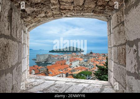 Vista dalla finestra in pietra dei tetti rossi e fortezza nella vecchia stoppa di Dubrovnik. Bella vista del mare blu, l'isola e il centro storico di Dubrovnik, C Foto Stock