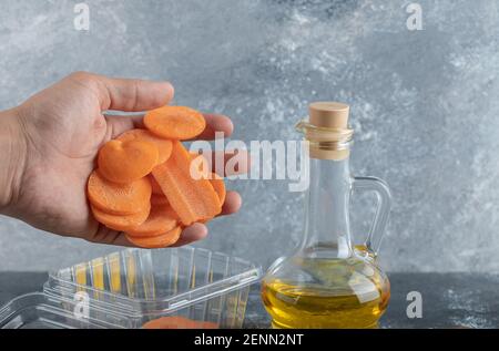 Mano maschile versando le fette di carota in un contenitore di plastica Foto Stock