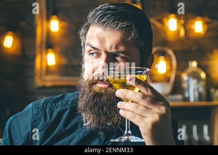 Hipster uomo con martini o liquore. Primo piano ritratto di uomo bearded che indossa il vestito e beve l'alcool. Concetto di festa per drink e celebrazioni. Foto Stock