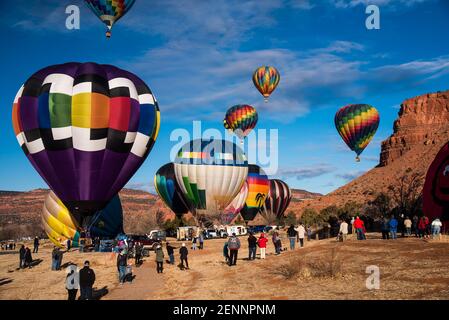 Kanab, Utah, USA, 19 febbraio 2021 - gli spettatori si riuniscono per guardare 30-40 palloncini ad aria calda che si innalzano sopra le scogliere rosse e il cielo blu di Kanab, Utah, USA. Foto Stock