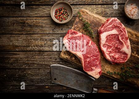 Varietà di bistecche fresche di carne prime all'Angus Black, New York, Ribeye e stagionatura su sfondo di legno, vista dall'alto Foto Stock