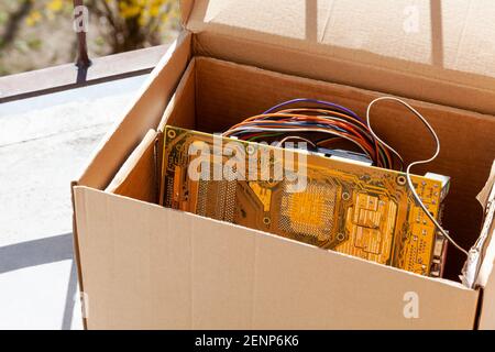 Buttare via i rifiuti elettronici, componenti pc obsoleti in una scatola di cartone, riciclaggio di rifiuti elettronici, vecchie parti di computer che distruggono, eco, sbarazzarsi di elettronica Foto Stock