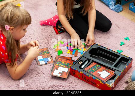 Due bambine in età scolare che giocano un gioco di Ubongo insieme. Attività per la famiglia durante il soggiorno a casa, giochi da tavolo per bambini, sorelle, fratelli e sorelle insieme Foto Stock