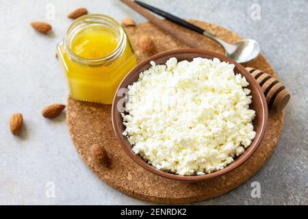 Ricco di calcio sano cibo. Tvorog, formaggio agricolo, formaggio di cagliata o formaggio da cottage in una ciotola con miele e mandorla su tavola di pietra. Foto Stock
