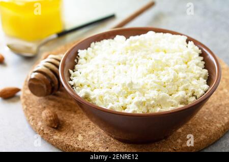 Ricco di calcio sano cibo. Tvorog, formaggio agricolo, formaggio di cagliata o formaggio da cottage in una ciotola con miele e mandorla su tavola di pietra. Foto Stock