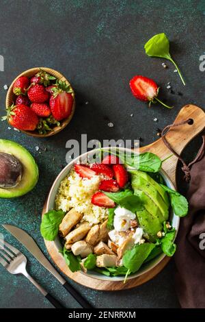 Cibo sano, concetto di menù dietetico, dieta chetogenica e dieta paleica. Insalata couscous con fragole, pollo alla griglia, avocado e formaggio feta su un Foto Stock