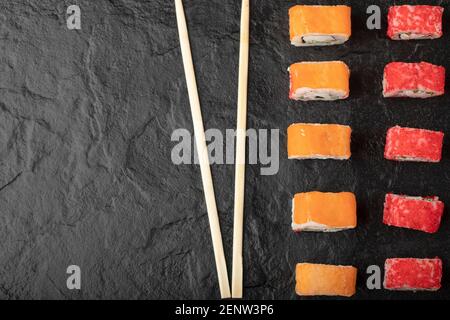 Deliziosi panini philadelphia e california sushi su superficie nera Foto Stock