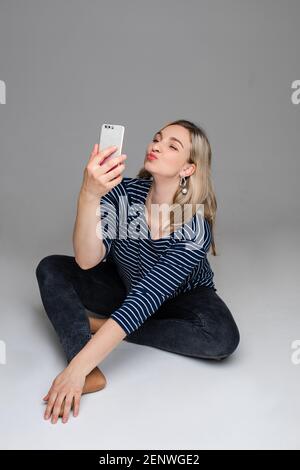 Ragazza con cellulare che prende selfie con anatra faccia. Foto Stock