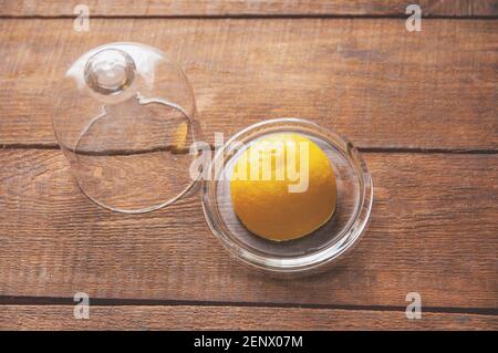 pezzo di limone si trova su una citronella di vetro con un coperchio su un tavolo di legno Foto Stock