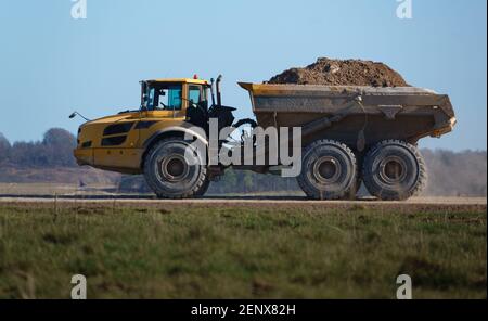 Gialle Volvo A40E dumper a terra articolato completamente carico con 25 tonnellate di carico che guida attraverso Salisbury Plain, Wiltshire UK Foto Stock