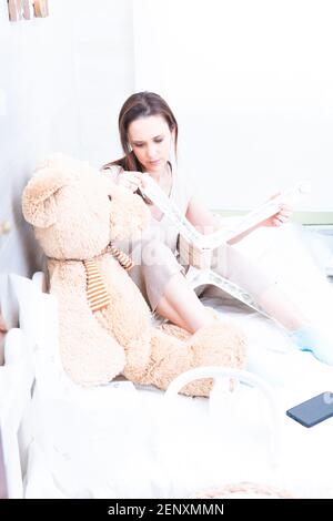 donna in casa vestiti montaggio di un seggiolone di alimentazione del bambino. Mobili assembly. Concetto cambia a casa per il bambino Foto Stock