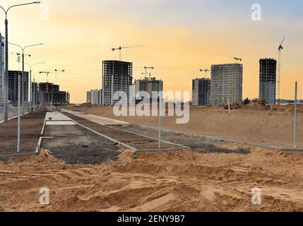 Spianare la sabbia per la posa di lastre e bordi di pavimentazione e blocchi di calcestruzzo in cantiere. Processo di installazione di mattoni di pavimentazione nel pedone Foto Stock