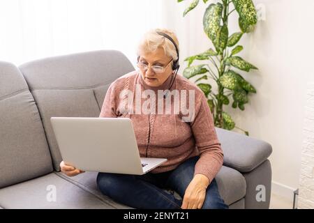 Donna anziana che usa un computer portatile a casa Foto Stock