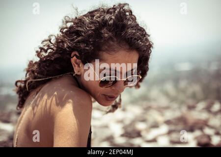 Forte attraente giovane donna messicana con capelli ricci e sole occhiali Foto Stock