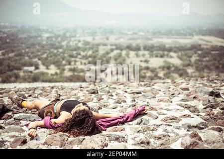 Giovane donna sdraiata sulle sacre rovine Maya in Messico Foto Stock