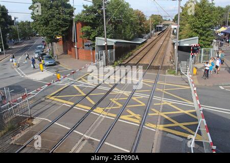 Un passaggio a livello ferroviario chiuso con auto e pedoni in attesa alle barriere chiuse. Highams Park, Londra Foto Stock