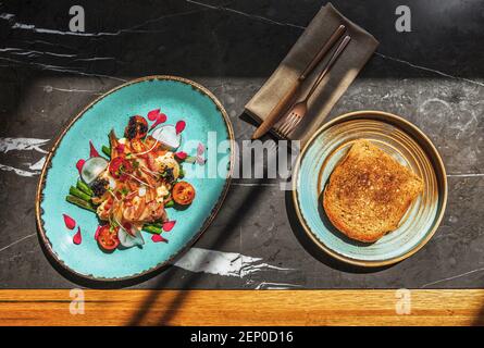 Uova con pancetta, asparagi e capesante su un piatto blu. Foto Stock