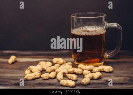 tazza di birra su un tavolo di legno arachidi in conchiglie primo piano su bevande alcoliche Foto Stock