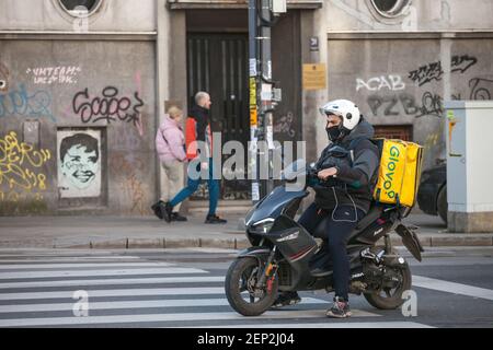 BELGRADO, SERBIA - 21 FEBBRAIO 2021: Uomo di consegna Glovo che indossa una maschera facciale respiratore protettivo a belgrado durante la crisi del Coronavirus Covid 19 Foto Stock